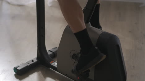 male-legs-on-pedals-during-training-on-stationary-bike-closeup-shot-healthy-lifestyle-and-fitness-at-home-or-gym
